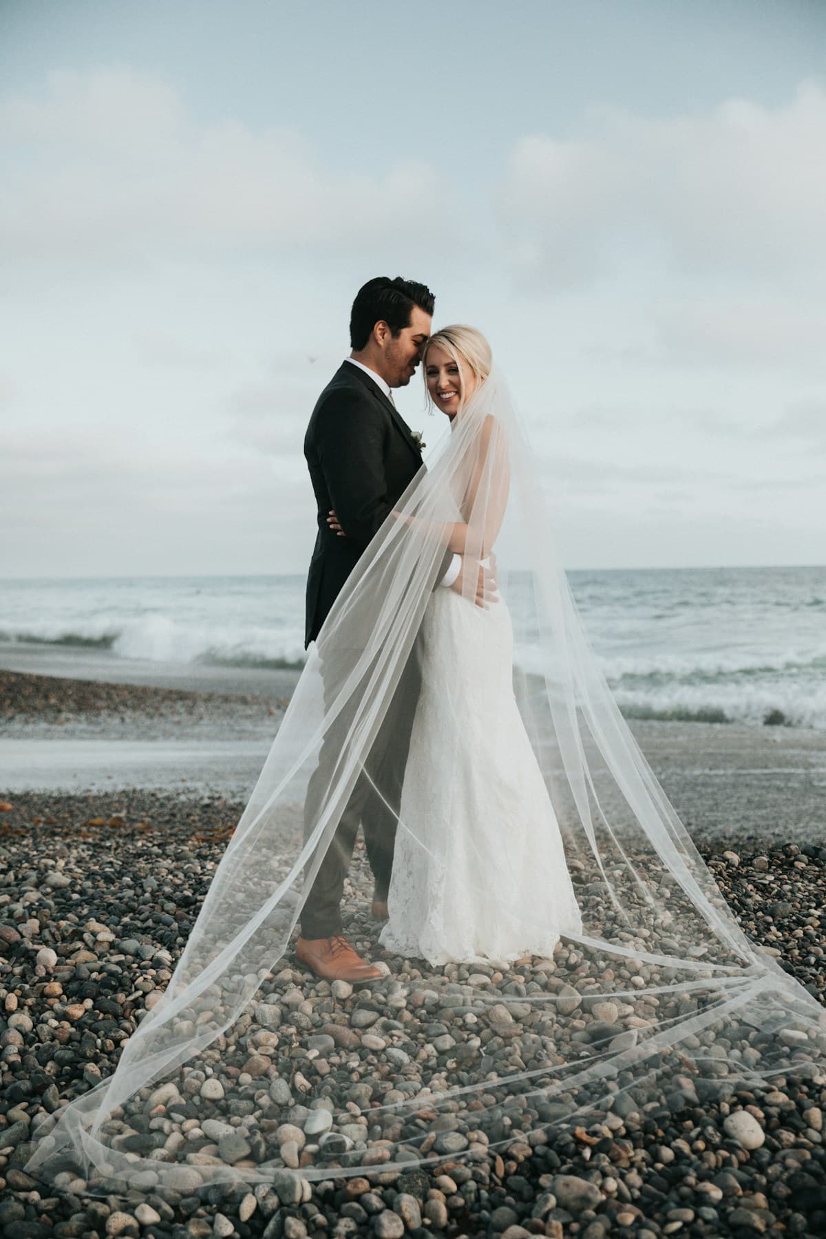 Outdoor wedding portrait of bride and groom with flowing veil